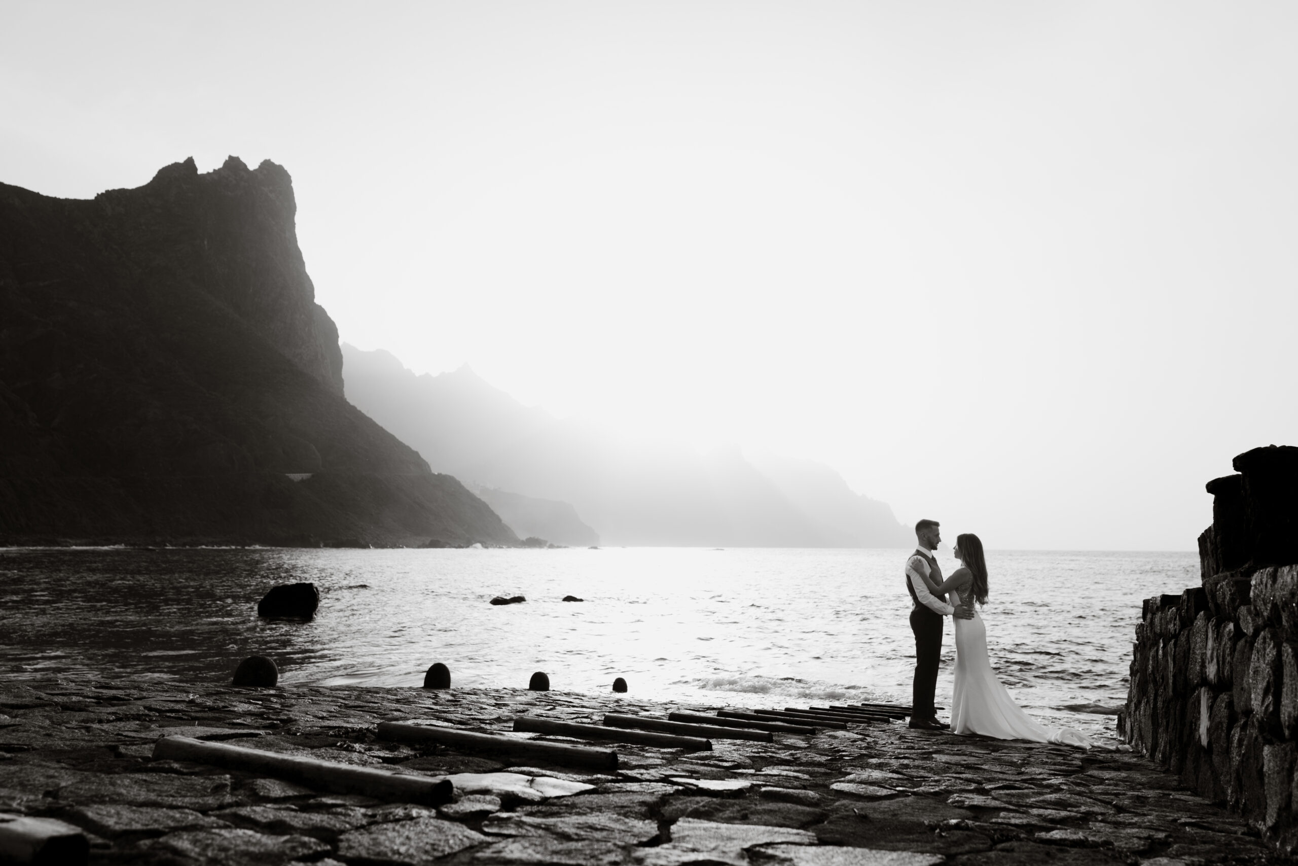 Pareja de novios junto al mar y los acantilados, fotografiada en blanco y negro.